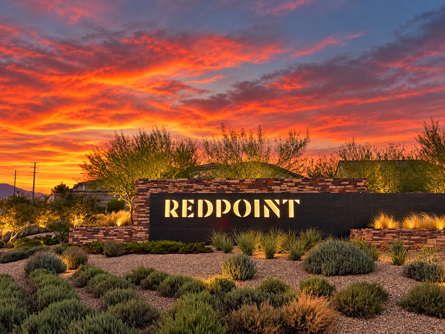 Illuminated Redpoint village entrance sign and desert landscaping at sunset in Summerlin, Las Vegas.
