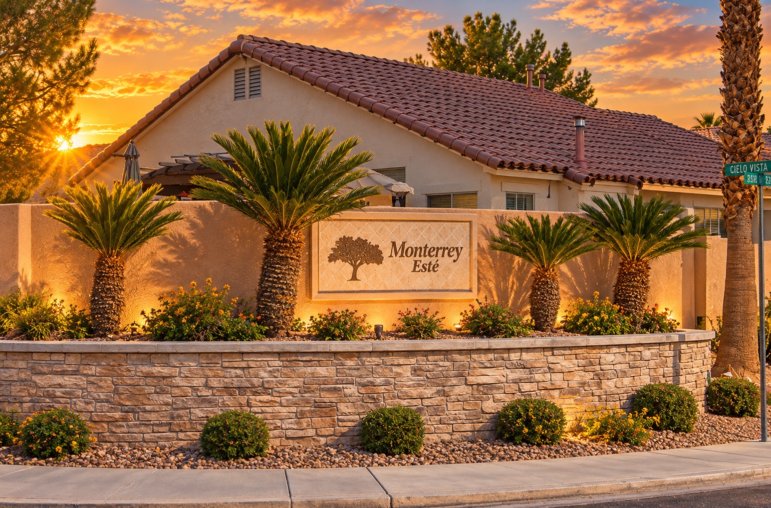 Monterrey Este entrance monument with palms and a tile-roof home at sunset in The Pueblo, Summerlin, Las Vegas